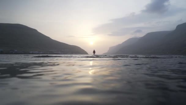 Homme debout au lever du soleil dans le lac peu profond — Video