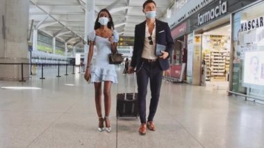 Havaalanı mağazalarından geçen cerrahi maskeli bir adam ve kadın.