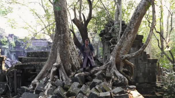 Bayon Tapınağı 'nın Ortasında İki Büyük Yaşlı Ağaç Arasında Yürüyen Adam — Stok video