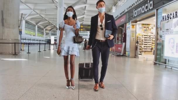 Man en vrouw dragen chirurgische maskers passeren Airport Stores — Stockvideo