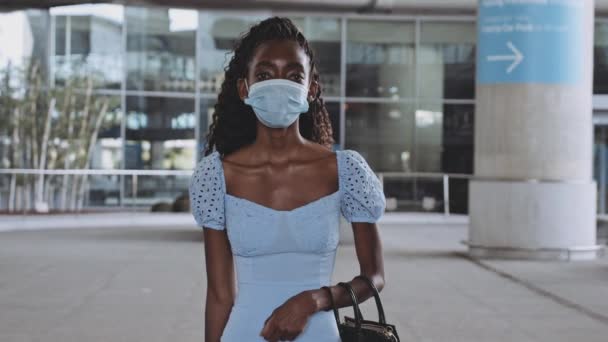 Женщина с лицом, покрытая хирургической маской с пустым терминалом аэропорта — стоковое видео