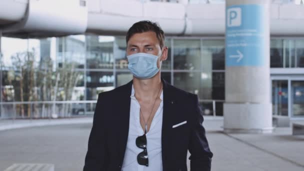 Goed uitziende mannelijke reiziger die in de luchthaventerminal loopt tijdens de Covid-19 pandemie — Stockvideo