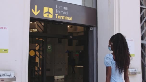 Covid-19 cartazes na parede no aeroporto e mulher passando pelo portão do aeroporto — Vídeo de Stock