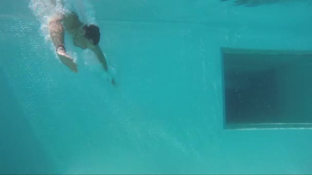 Mann springt und schwimmt unter Wasser zur anderen Seite des Beckens — Stockvideo