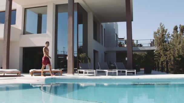 Jeune voyageur plonge dans la piscine et éclaboussures d'eau — Video