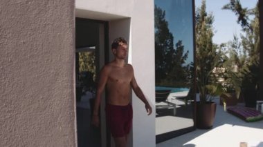 Güneşli bir günde açık havuza doğru yürüyen erkek modelinin yan görüntüsü