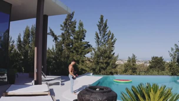 Trek in shot van de mannelijke toerist door het zwembad kant doet Bicep krullen — Stockvideo