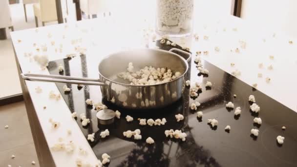 Pan na kuchence z popcornem wyskakujące z patelni i na blacie kuchennym — Wideo stockowe