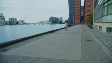 Rıhtım boyunca Bisiklete Binen Kadın