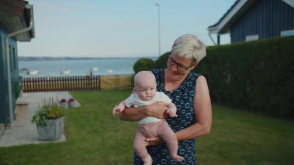 Бабушка держит малышку в саду — стоковое видео