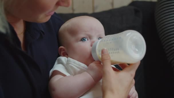 Bebé de ojos azules alimentándose de biberón — Vídeo de stock