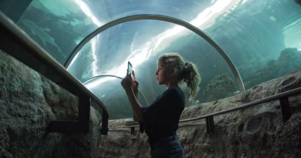 Menina bonita no meio do túnel subaquático tirar fotos com seu telefone — Vídeo de Stock