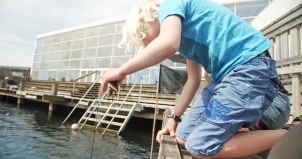 Broers en zussen door de rand van dok leunend over naar vangen krab met strengen — Stockvideo