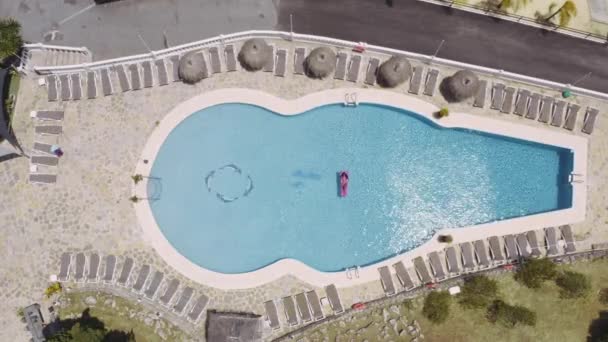 Aerial Topdown Shot de una mujer relajante junto a la piscina acostada sobre un inflable rosa — Vídeos de Stock