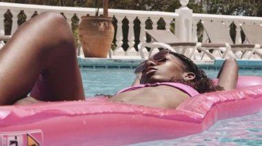 Güneş gözlüğü takan bir kadın havuzda yüzüyor.