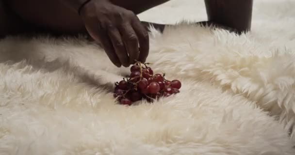 Naken man plockar upp druvor att äta — Stockvideo