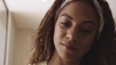 Kıvırcık saçlı, yana bakan, aşağı bakan ve gülümseyen güzel bir kadın.