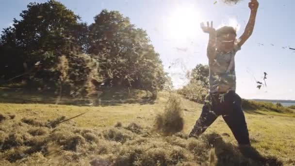 Jongen gelukkig gooien Mown Grass In de zomer — Stockvideo