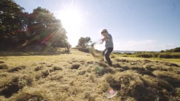 Garçon jouer par jeter herbe en été — Video