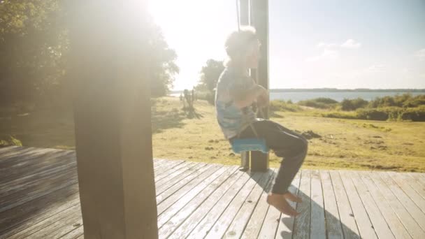 Descalzo chico en verano porche swing — Vídeo de stock