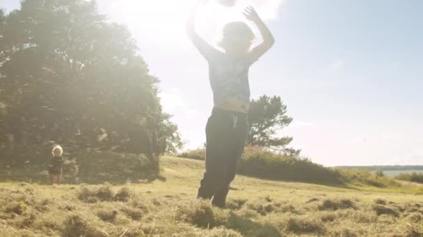 Молоді хлопці бавляться з травою на лузі — стокове відео