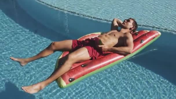 Genç adam karpuz havuzunda güneşleniyor. — Stok video