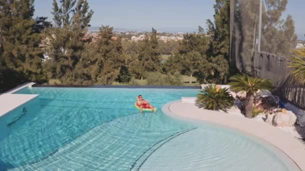 Mann entspannt sich auf aufblasbarer Wassermelone im Pool — Stockvideo