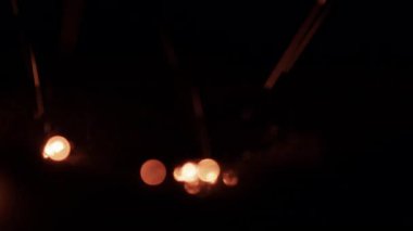 Ilık, titrek bir ateş, parlak kıvılcımlar saçar. Hayalperest altın bokeh daireleri ile karanlık bir arkaplanda. Sıcak ve büyülü bir atmosfer yaratır.