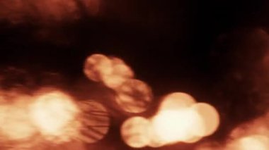 Parlayan altın şömine ışığı Bokeh, karanlık bir arka planda yavaşça parlayarak sıcak ve rüya gibi bir atmosfer yaratıyor.