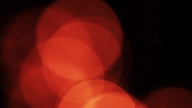 Sıcak, parıldayan Bokeh daireleri siyah bir arkaplan üzerinde sürükleniyor, rahat ve çevresel bir görsel etki yaratıyor.