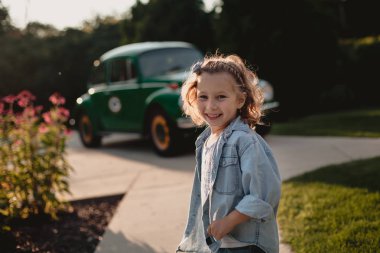 Eski moda arabanın yakınında oynarken gülümseyen küçük kız