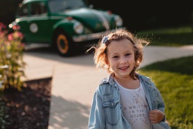 Eski moda arabanın yakınında oynarken gülümseyen küçük kız