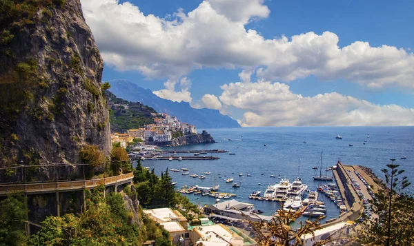 The view of Amalfi coast. This is on the south of Italy in Europe. The city stands on cliffs above the sea. There are boats on the sea.