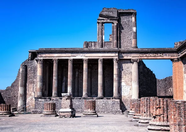 A stone column and ruin of the city. Behind it is blue sky. It is situated in Pompei, Italy in Europe.