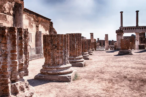 A stone column and ruin of the city. Behind it is blue sky. It is situated in Pompei, Italy in Europe.