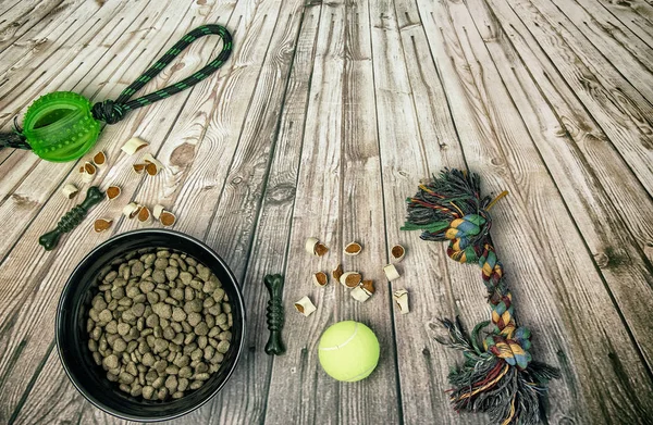 Dog bowl with food, drag-and-drop and tennis ball on a wooden floor in retro style.