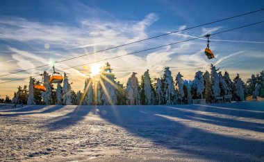 The chairlift in the mountains. There is a beautiful sunrise. It is situated in Ore Mountains in western Bohemia. Blue sky is in the background. clipart