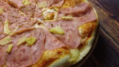 4 k video close-up bir pizza hawaii jambon, peynir ve ananas ile. Pizza baharat - fesleğen ve kekik serpilir. Bu pizza tablo dönen görünümü aşağı oldu.