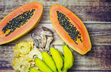Taze papaya, küçük taze muz, kurutulmuş ananas ve ahşap arka plan üzerinde kurutulmuş küçük muz