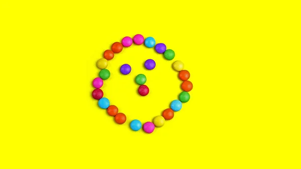 Chocolade colorido smarties no fundo amarelo. É forma de sorriso . — Fotografia de Stock