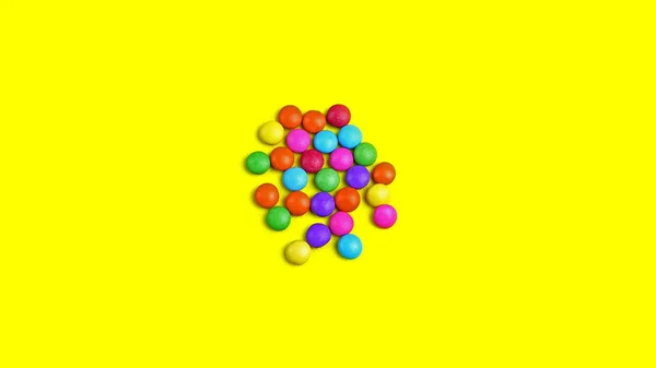 Colorful chocolade smarties on the yellow background.