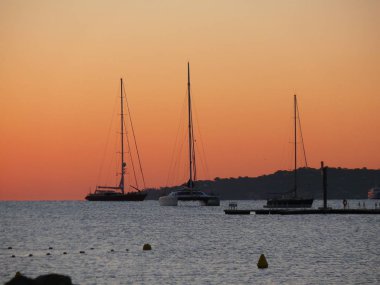 Port Saint Tropez Fransa Avrupa'nın yakınındaki kumsalda romantik gündoğumu. Denizde gemiler ve yatlar vardır.