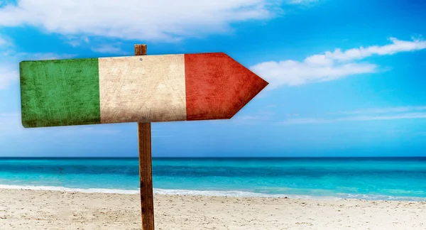 木のテーブルでイタリアの国旗は、ビーチの背景にログインします。それはイタリアの夏サインです。. — ストック写真