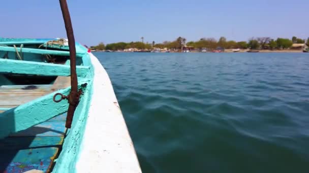 4K video av trä blå och vit kanot flyter på vattenytan. Det är en havslagun i Afrika, Senegal. Det är Birds National Park. Bakgrunden är suddig. — Stockvideo