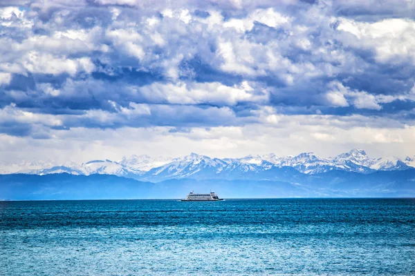 Le navire sur le lac de Constace, Bodensee. En arrière-plan se trouvent de grandes montagnes enneigées Alpes. Le lac se trouve en Allemagne, Autriche et Suisse Il y a de l'eau cristalline bleu clair. — Photo