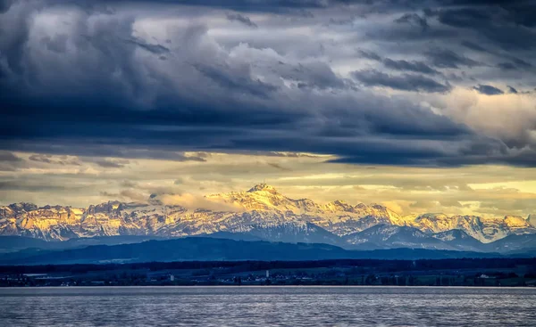 Kota Constance di Danau Constace, Bodensee. Pemandangan matahari terbenam di pegunungan bersalju Alpen. Thelake terletak di Jerman, Austria dan Swiss. — Stok Foto