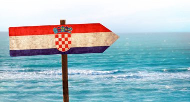 Plaj arka planda ahşap masa tabelası Hırvatistan bayrağı. Deniz ve mavi gökyüzü açık su ve plaj vardır