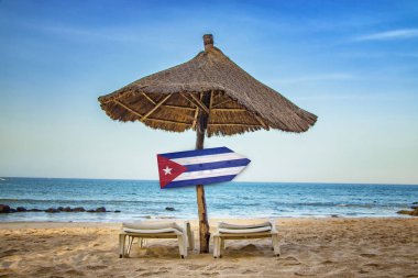 Ahşap ok tabelası üzerinde Küba bayrağı. Plajda iki şezlong ve bir güneş şemsiyesi vardır. Bu açık bir deniz ile tropikal bir cennet.
