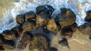 Kum plajı ve berrak okyanus havadan görünümü. Üst görünüm deniz dalgaları ve taşlar Hd video, tropikal kumlu plaj ve dalgalar üzerinde uçan, gün doğumu var. Tropik bir cennet..