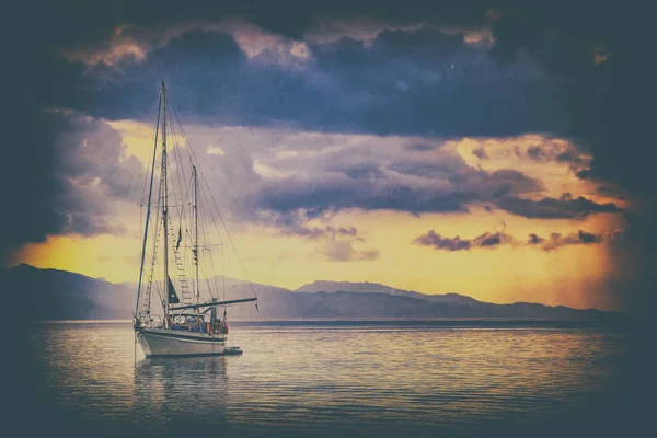 Foto lama dalam gaya vintage sebagai latar belakang alami. Ada sebuah kapal pesiar di laut Mediterania saat matahari terbit, Cagliari, Italia. matahari menerangi pulau dengan warna emas yang indah . — Stok Foto